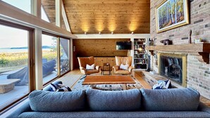 Ein gemütliches Wohnzimmer mit Kamin, großen Fenstern und einer Bücherwand.