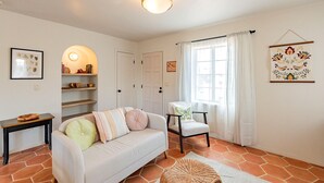 Een woonkamer met een bank, stoel, planken en een wandlamp.