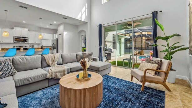 A modern living room with a grey sofa, a round coffee table, and a blue rug. - 9 Miles to Disney: Themed Rooms, Pool & Theater (Kissimmee)