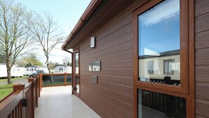 A wooden exterior with a glass door and a small sign. - Cormorant - Luxury Lodge, Close to the Beach (Tenby)