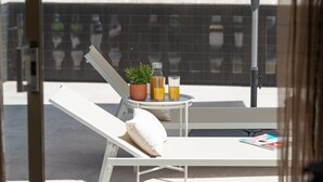 A sunlit balcony with a white lounge chair, a small table with a potted plant, two glasses of orange juice, and a bottle of water. - Villa Hilary with private pool near Playa de Muro (Muro)