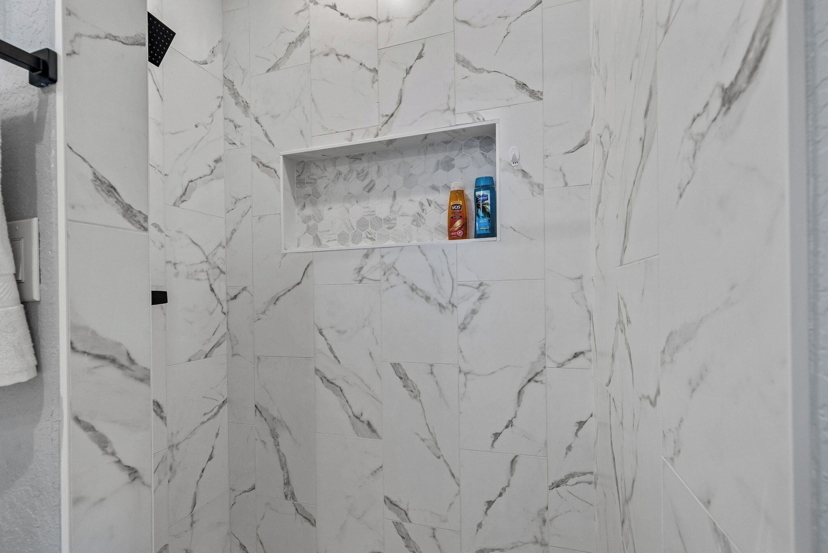Ein Badezimmer mit Marmorfliesen und einem Ablagefach für Toilettenartikel.