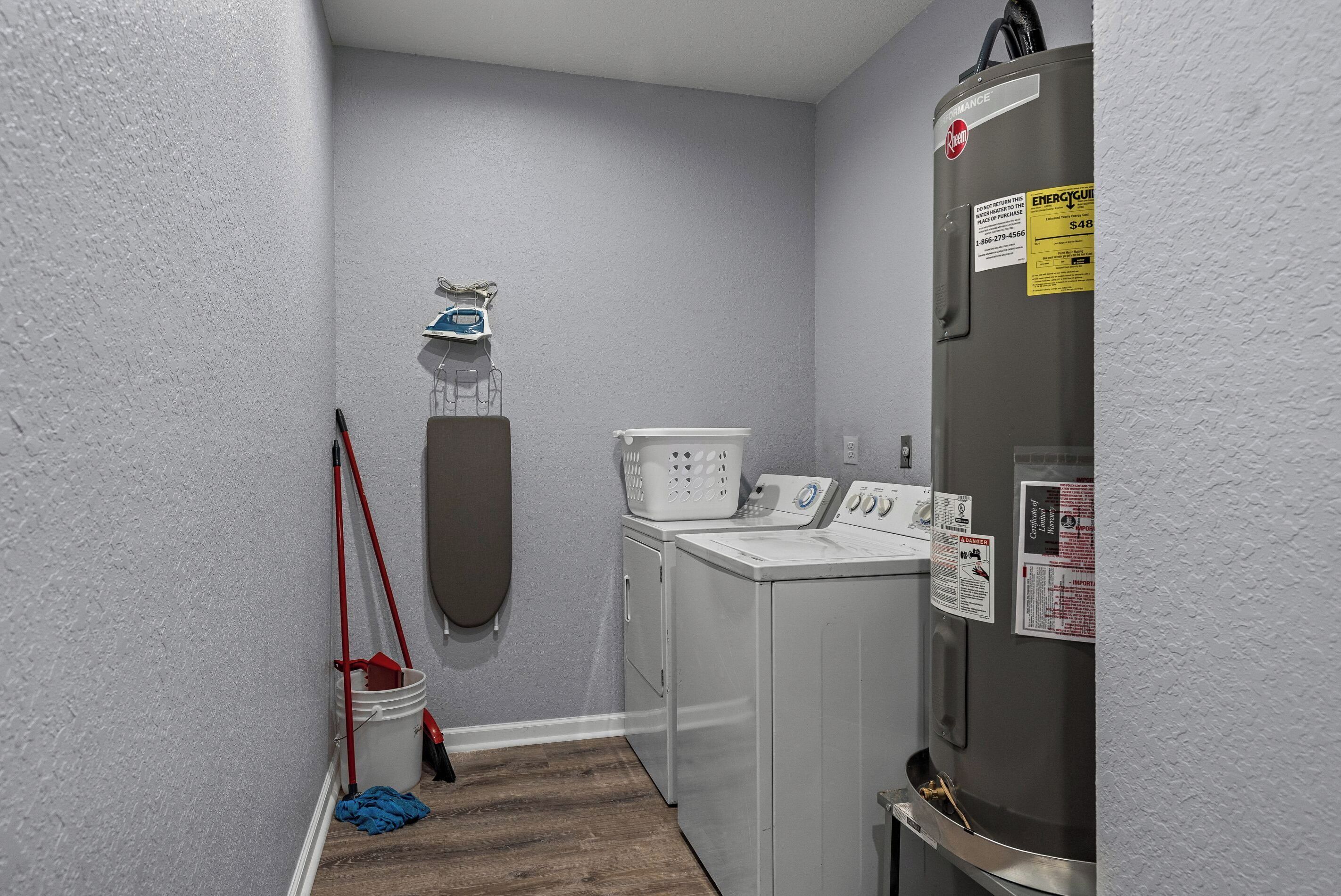 A laundry room with a washing machine, dryer, and ironing board.