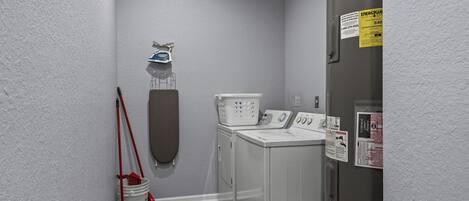 A laundry room with a washing machine, dryer, and ironing board.