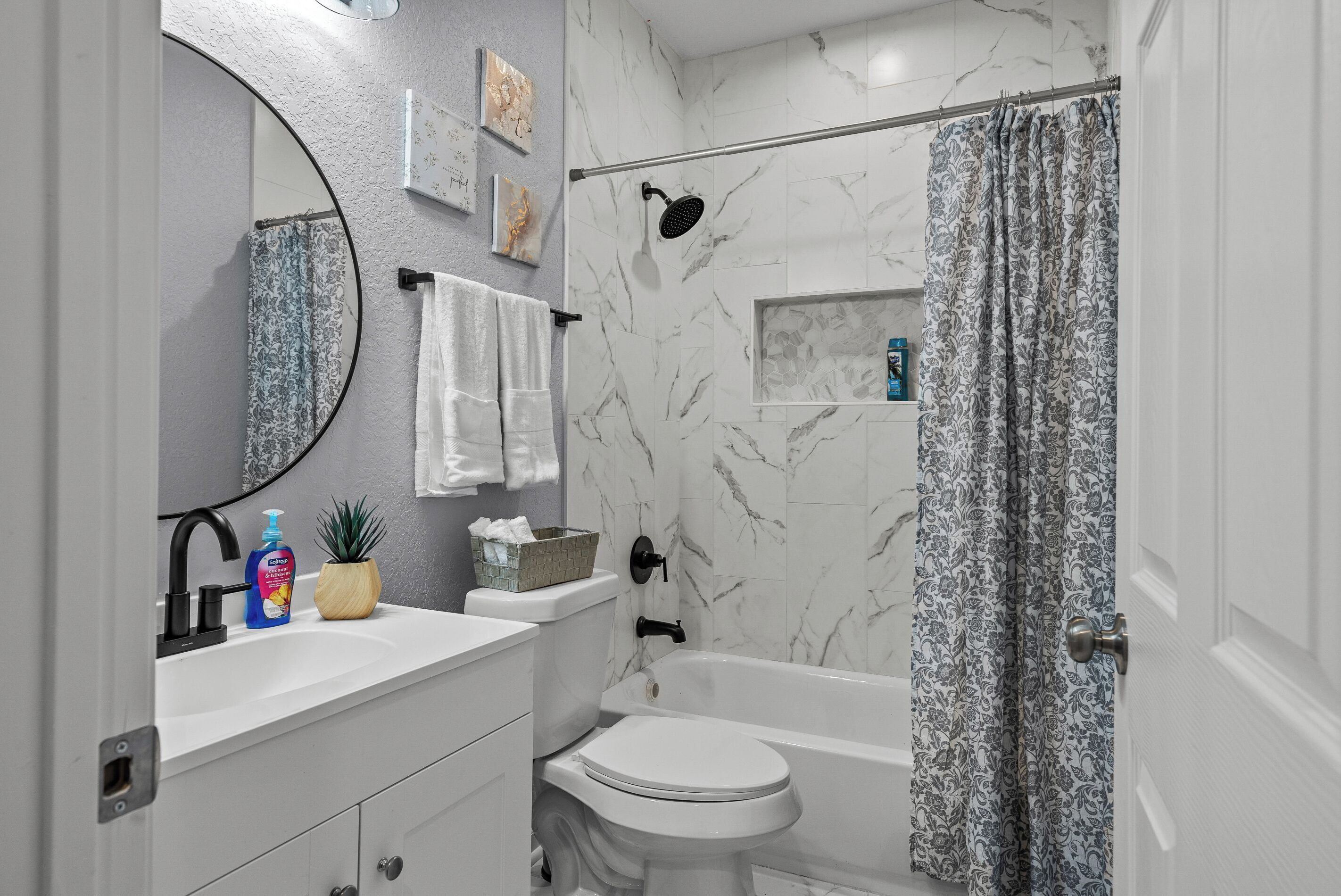 Une salle de bain avec un lavabo blanc, des toilettes, une baignoire et un rideau de douche.