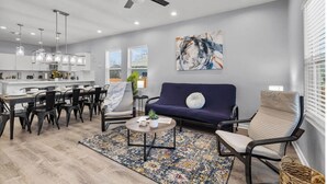 Un salon moderne comprenant un coin repas, un ventilateur de plafond et un grand tableau abstrait accroché au mur.