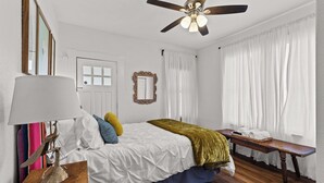 Ein Schlafzimmer mit Bett, Nachttisch, Lampe und Deckenventilator.