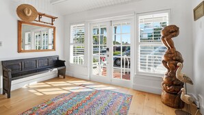 Una habitación con un banco de madera, un espejo grande, un tapete colorido y una escultura de madera original.