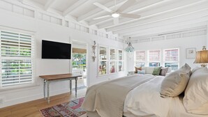 Un dormitorio con una cama grande, un ventilador de techo y un televisor montado en la pared.