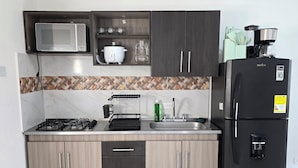 A modern kitchen with a microwave, stove, and refrigerator. - PILARICA GARDENS (Medellín)