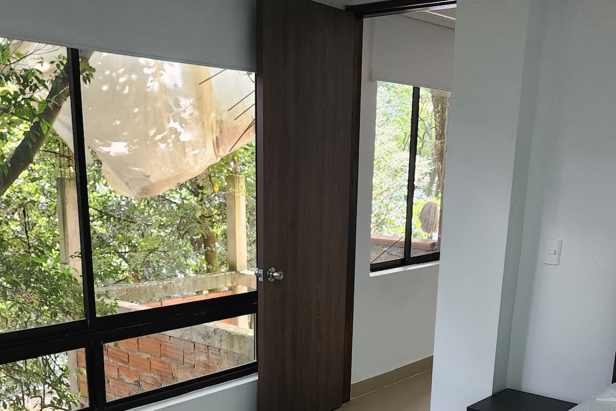 A bedroom with a bed, a window, and a door.