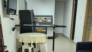 A compact living space with a dining area, a sofa, and a kitchen backsplash. - PILARICA GARDENS (Medellín)