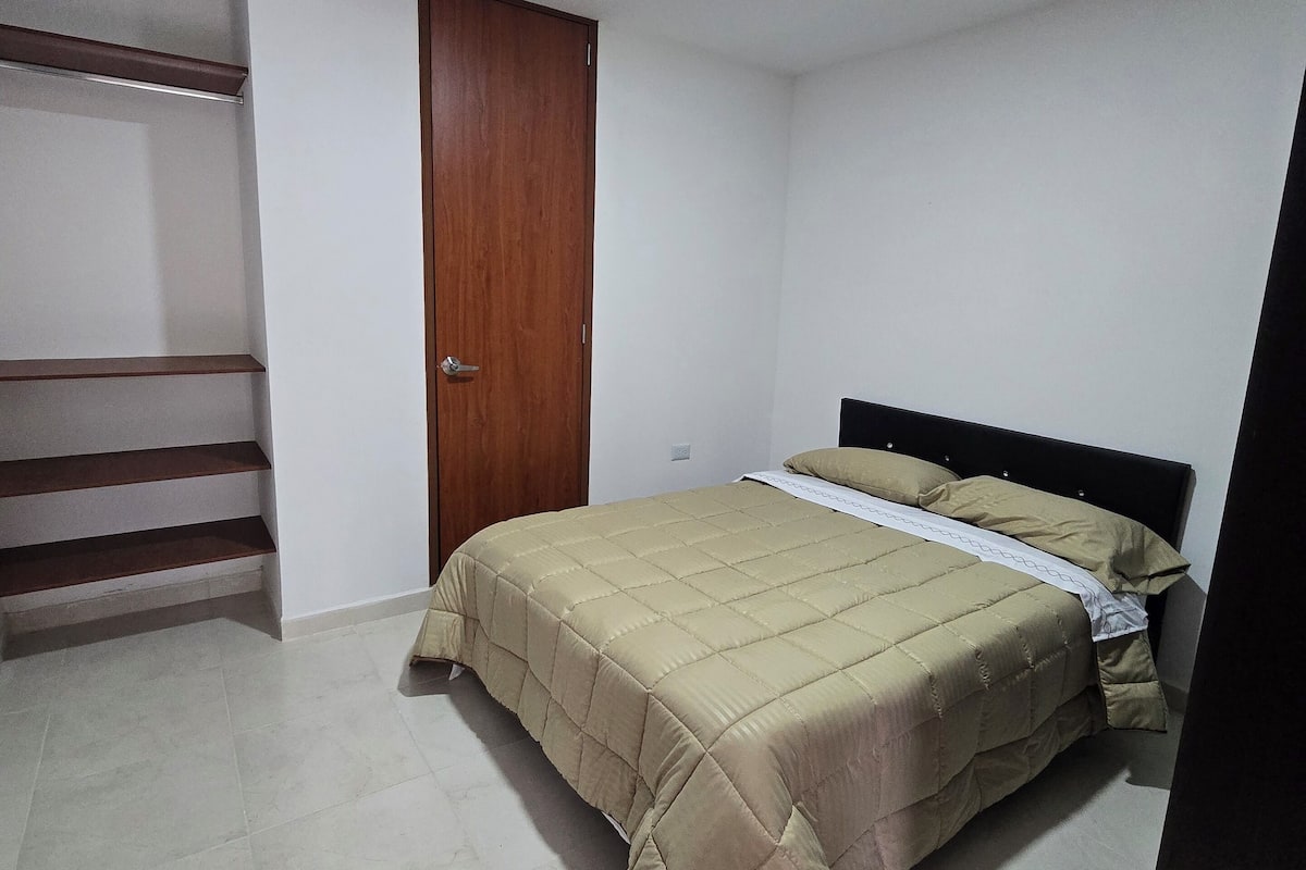 A bedroom with a bed, a wooden door, and a staircase.