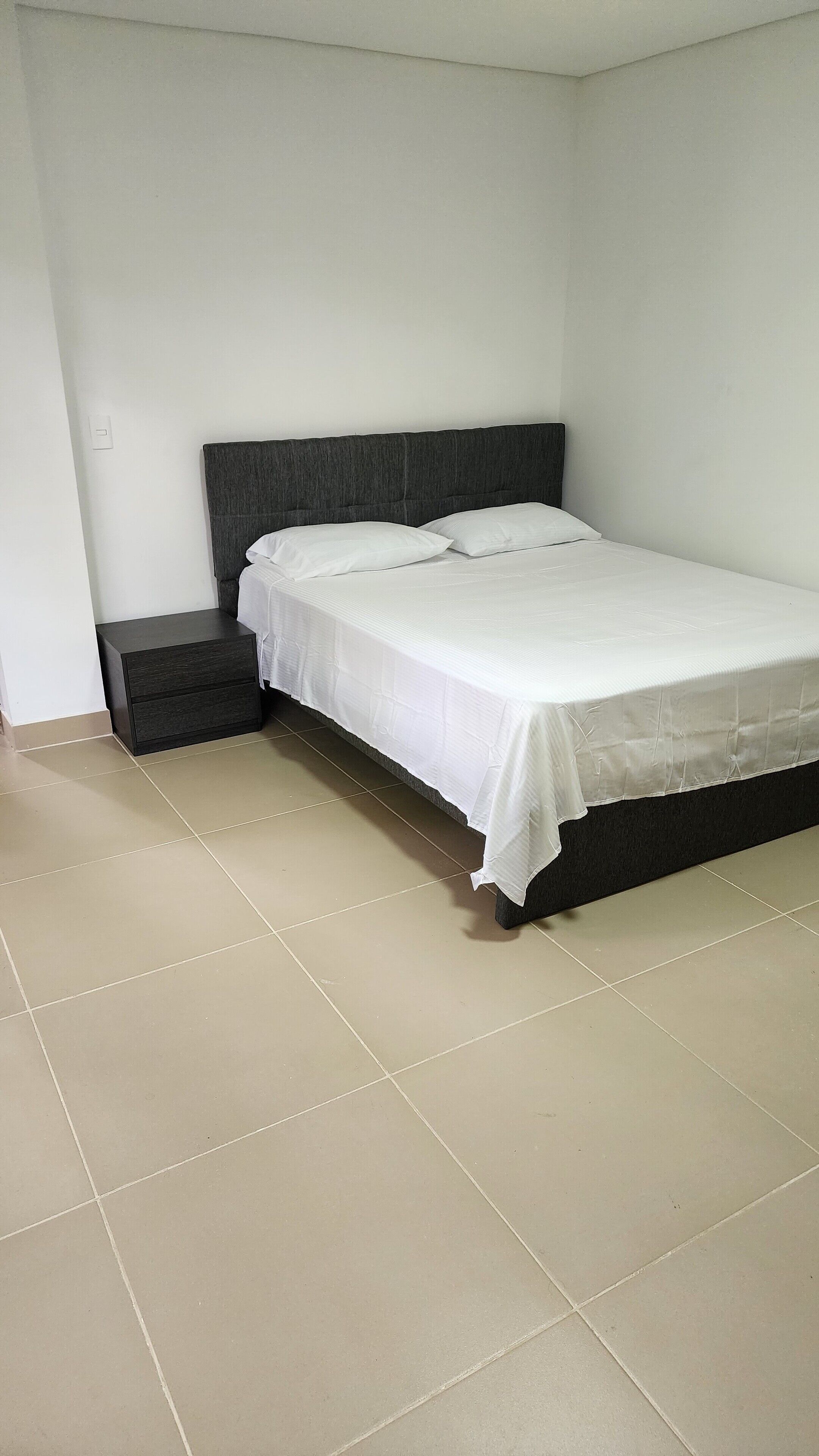 A bedroom with a bed, a nightstand, and a small drawer unit.