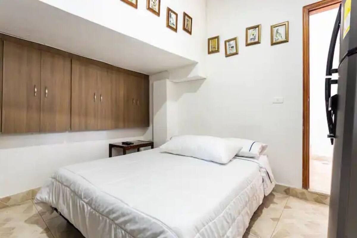 A bedroom with a bed, wooden wardrobe, and a small table.