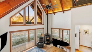 Un loft spacieux doté de grandes fenêtres, d’une cheminée et d’un ventilateur de plafond.