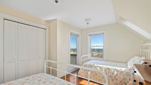 A bedroom with two beds, a wardrobe, and a view of the outdoors. - Sunshine & Seascapes, Biddeford Pool (Biddeford)