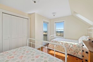 Ein Schlafzimmer mit zwei Betten, einem Kleiderschrank und Blick ins Freie.