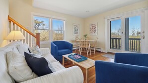 A living room with a sofa, armchairs, a coffee table, and a dining area with chairs and a table. - Sunshine & Seascapes, Biddeford Pool (Biddeford)