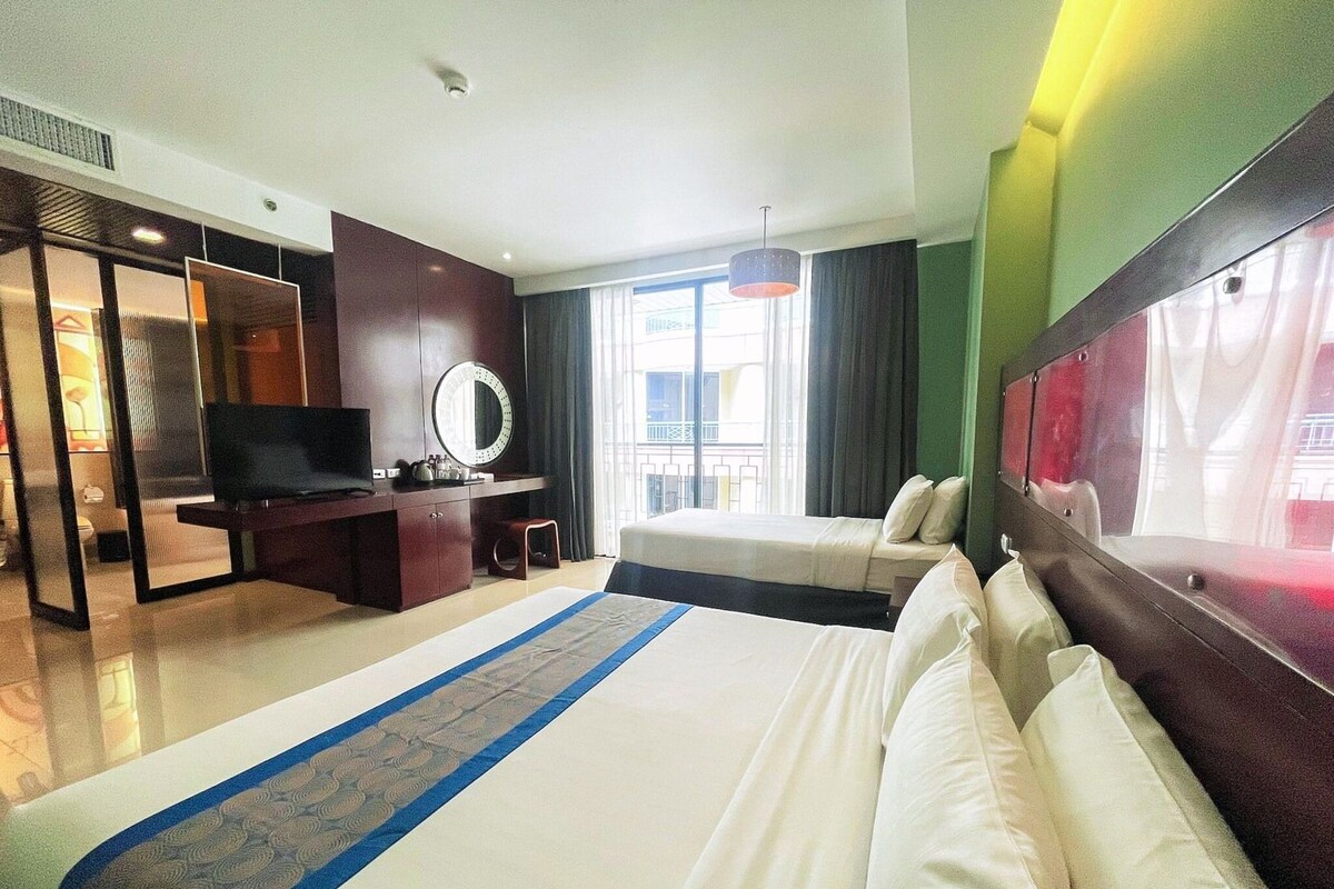 Une chambre d’hôtel avec un lit, un bureau avec une télévision, un miroir et une vue sur l’extérieur.