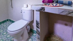 A bathroom with a toilet, a shower, and a sink.