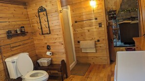 A wooden cabin bathroom with a toilet, sink, and shower.