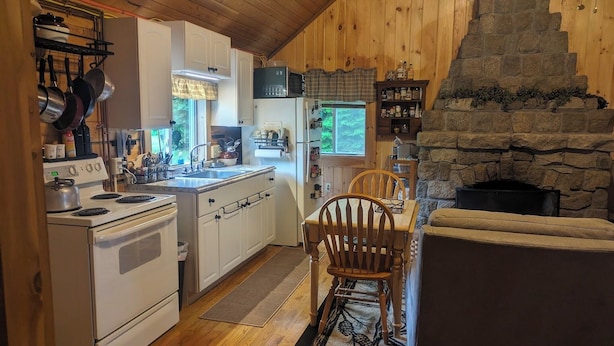 Une cuisine de taille réduite avec des meubles blancs, une cuisinière et une cheminée en pierre.