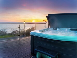 Un jacuzzi sur un balcon avec vue sur le coucher de soleil.