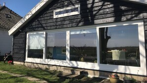 A house with a large window, a small attached garage, and a sloped roof.