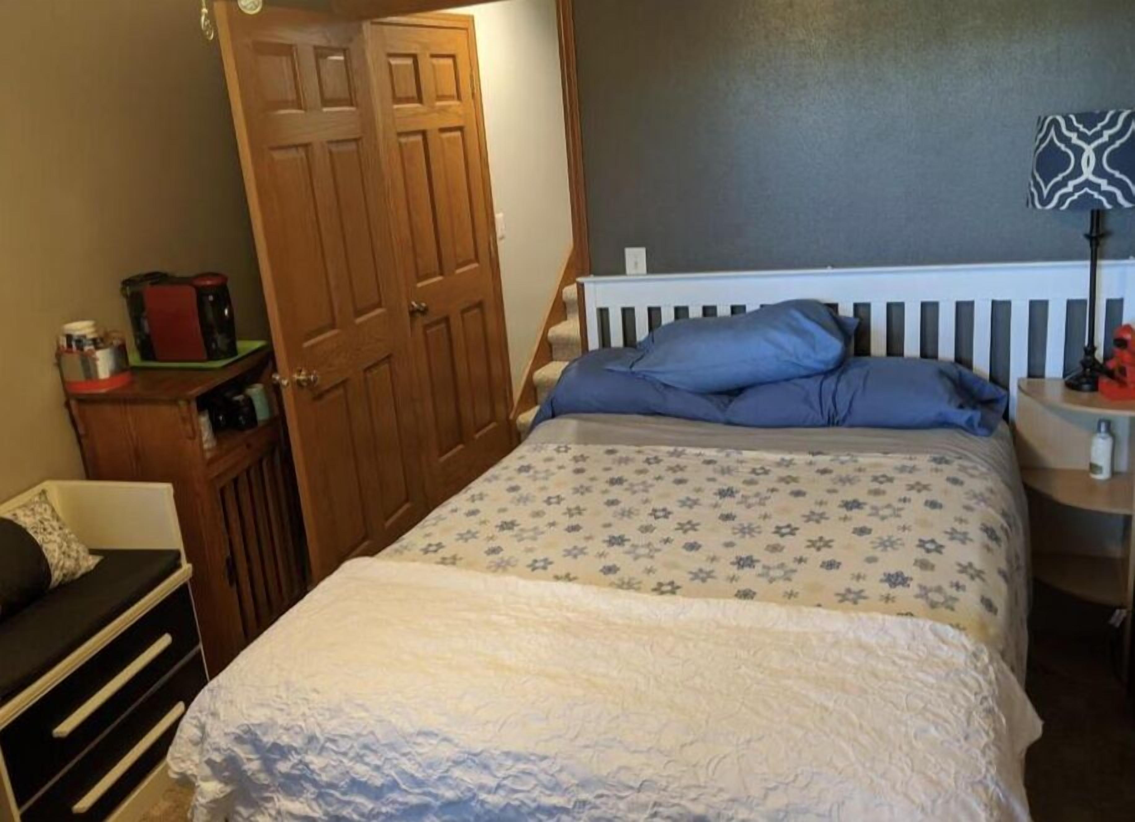 A bedroom with a bed, a nightstand, a dresser, and a wardrobe.