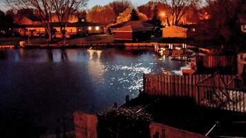 A nighttime view of a residential area with a body of water, houses, and a prominent full moon in the sky.
