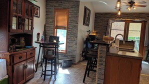 A kitchen with a stone backsplash, wooden cabinets, a dining area with stools, and a bar area with a sink. - Lake Channel 'Brewhaus' Townhouse: 2 bedrooms with 6 levels on Lake Winnebago (Oshkosh)