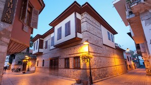 A stone building with a balcony and a sign that reads "THANAS." - Perge Pine Green (Antalya)