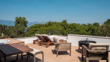 Eine Dachterrasse mit Holzmöbeln, einem Whirlpool und Blick auf die Berge.