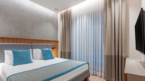 A modern hotel room with a large bed, wooden headboard, and a TV on the right. - Perge Pine Green (Antalya)