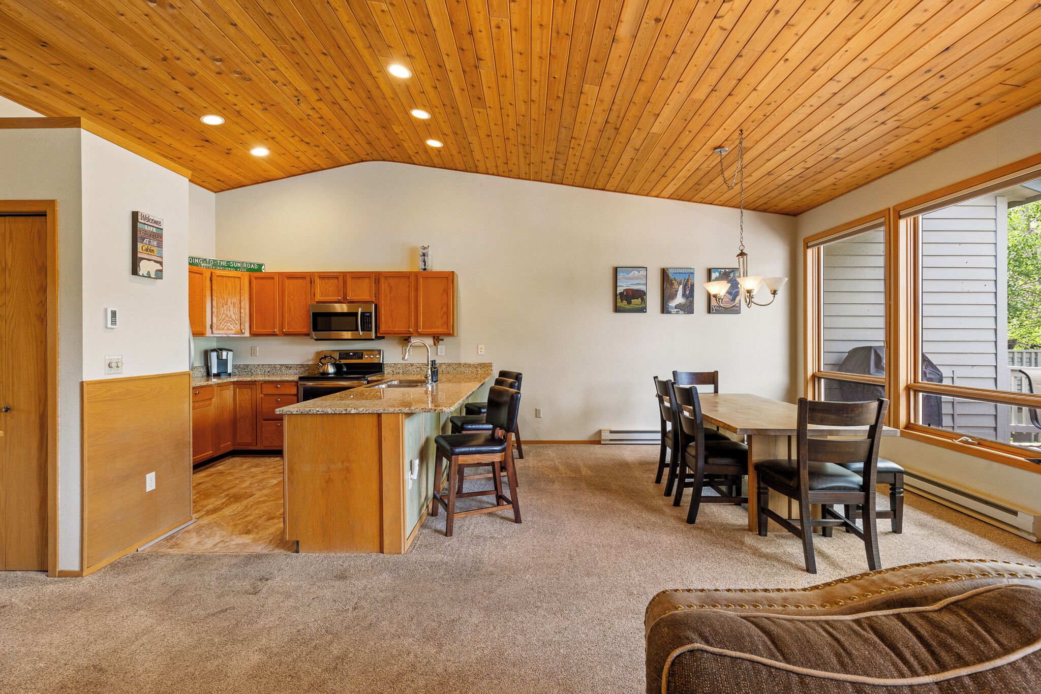 A spacious kitchen with wooden cabinets, a central island, and a dining area with chairs.
