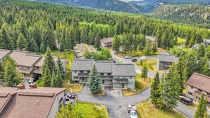 A residential area with houses, a large building with a flat roof, and a mountain in the background. - Woodbine Cabin | Big Sky (Big Sky)