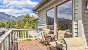 A wooden deck with outdoor furniture, a white railing, and a mountain view. - Woodbine Cabin | Big Sky (Big Sky)