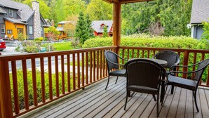 Une terrasse en bois, agrémentée de mobilier d’extérieur, qui offre une vue sur un quartier résidentiel avec ses maisons et sa verdure.