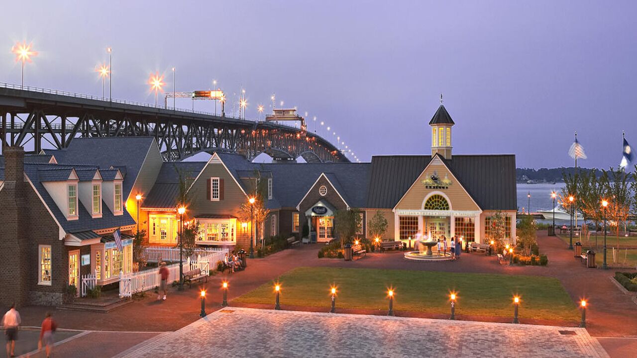 A waterfront hotel with a large building featuring a prominent tower and a covered patio area.