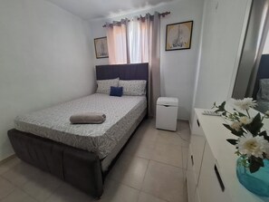 Une chambre à coucher comprenant un lit, une table de chevet, un miroir et un petit appareil électroménager blanc.