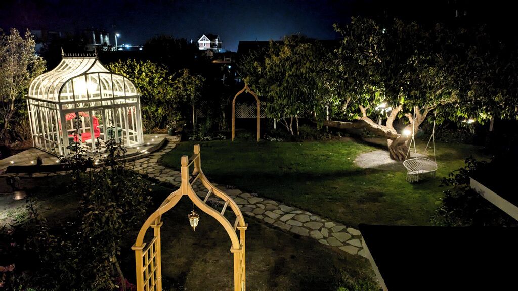 Un jardin agrémenté d’un belvédère, d’une balançoire et d’un sentier en pierre.
