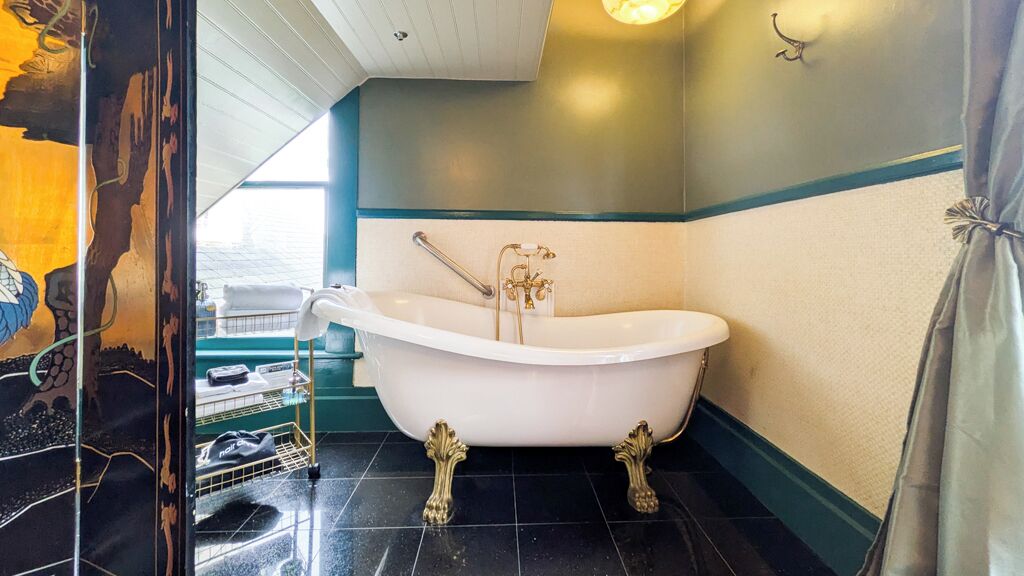 A bathroom with a freestanding bathtub, a towel rack, and a window with a view of the sea.