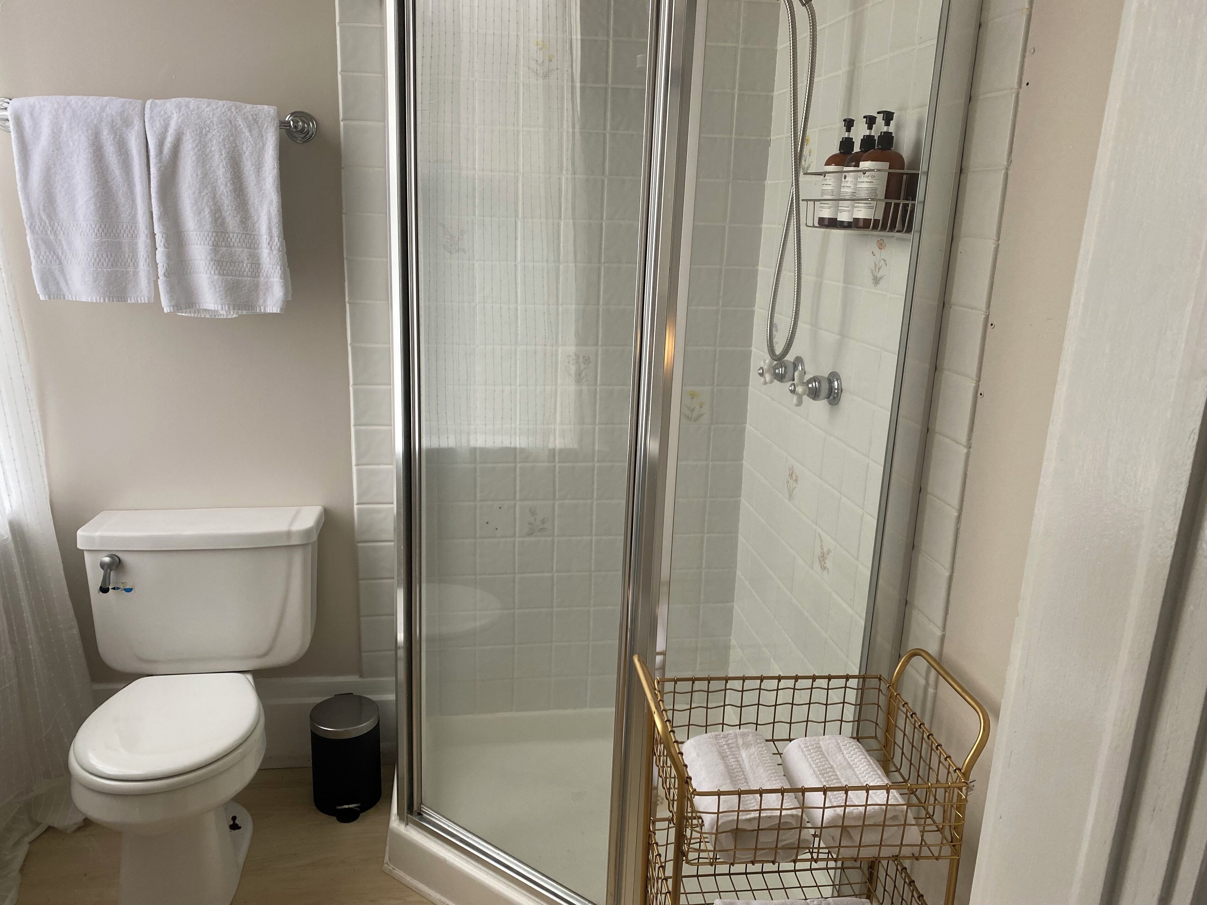 Un baño con inodoro, cabina de ducha y toallero.