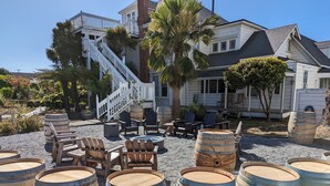 A coastal property with a large house, outdoor seating, and multiple wooden barrels. - The Weller House (Fort Bragg)