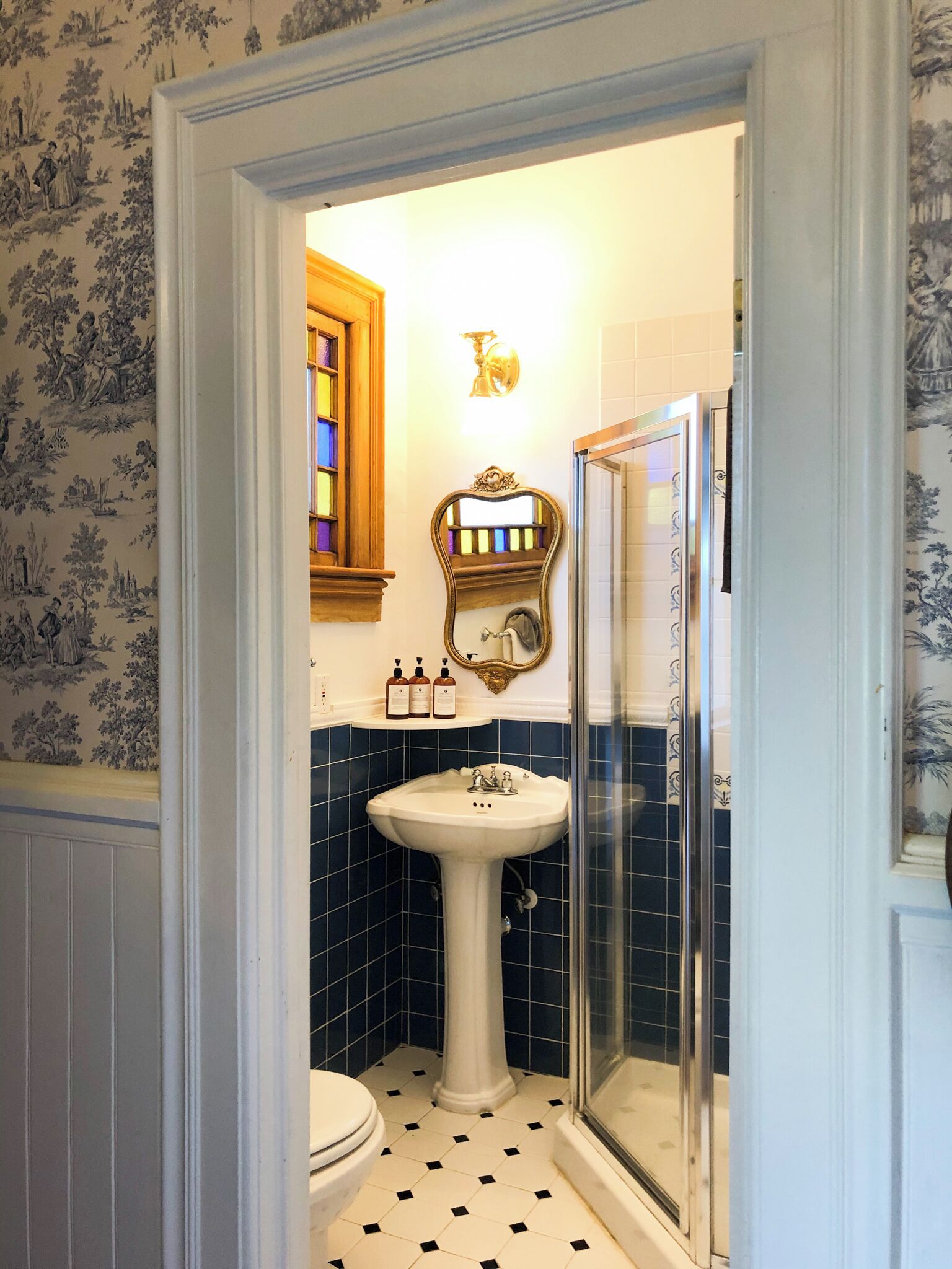 A bathroom with a pedestal sink, a mirror, and a shower.