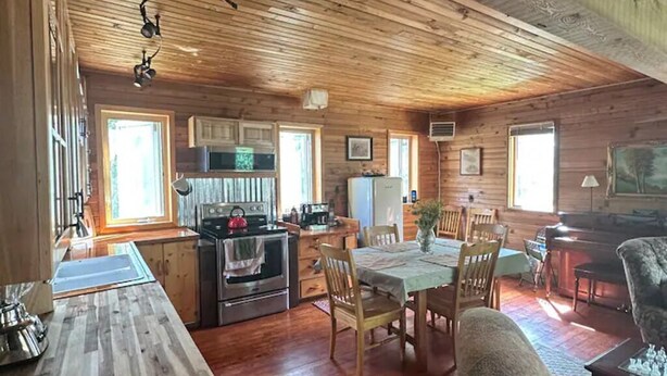 A wooden cabin interior with a kitchen, dining area, and a cozy living room. - Cedar Cabin Cozy 2-Bedroom next to Glacier Park (East Glacier Park)