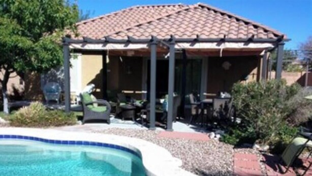 Un espace extérieur abrité comprenant une piscine, du mobilier de jardin et une pergola.