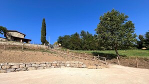 A stone house with a sloped roof, surrounded by a stone retaining wall and a wooden fence. - Il Moro-Gemme del Casentino (Castel Focognano)