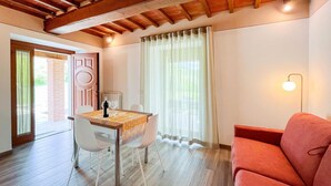 A dining area with a table set for two, a red sofa, and a lamp. - Il Moro-Gemme del Casentino (Castel Focognano)
